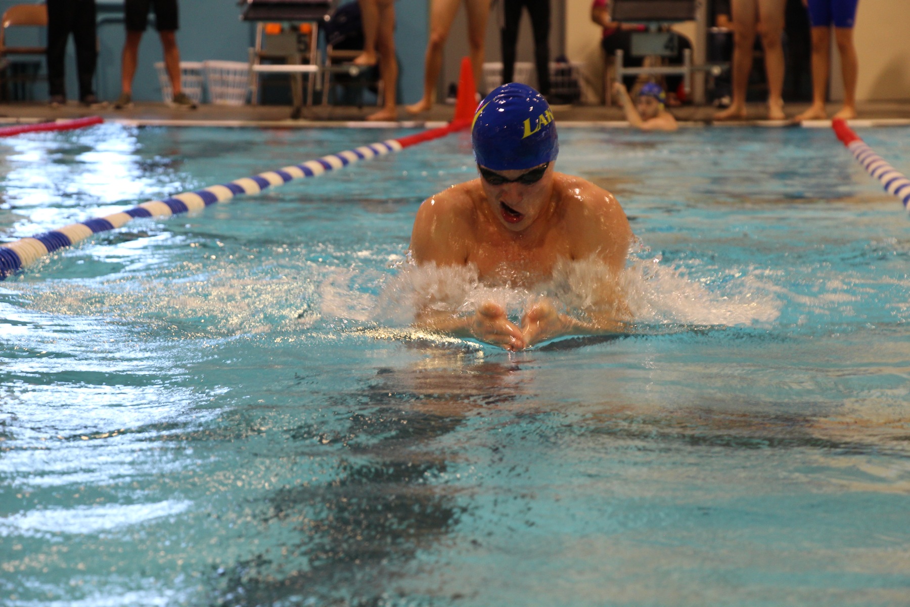 Val Trussov swims his breaststroke leg of the Medley Relay as teammate Jesse Lattin looks on after finishing his backstroke leg.